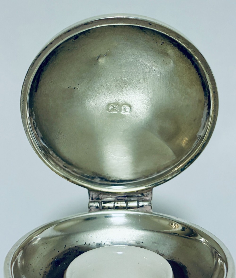 A polished silver capstan inkwell featuring a broad circular base, a tapered central waist, and a hinged flat lid. View IX