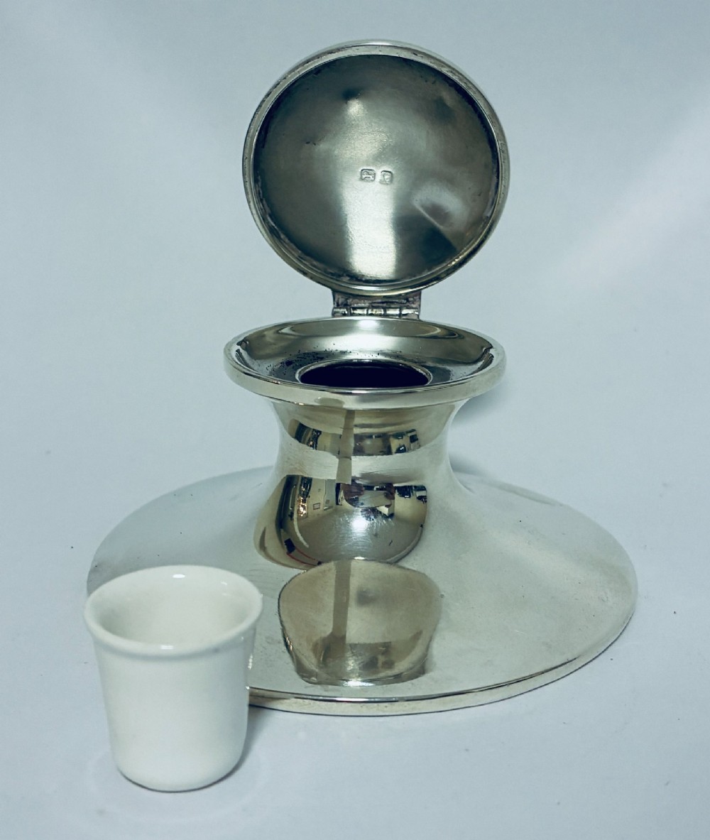 A polished silver capstan inkwell featuring a broad circular base, a tapered central waist, and a hinged flat lid. View XI