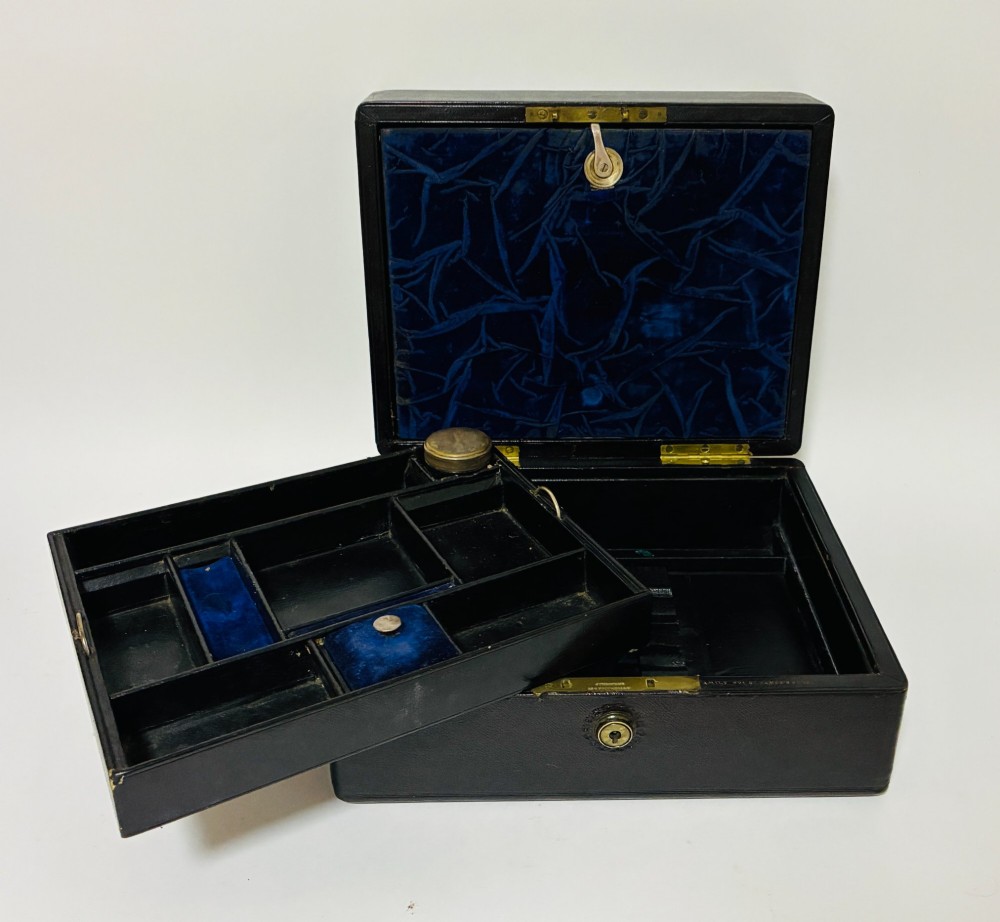 An open Victorian dark brown leather dressing case with a blue velvet-lined lid, brass lock, and compartmentalised interior sitting inside an outer leather travel box. View IV