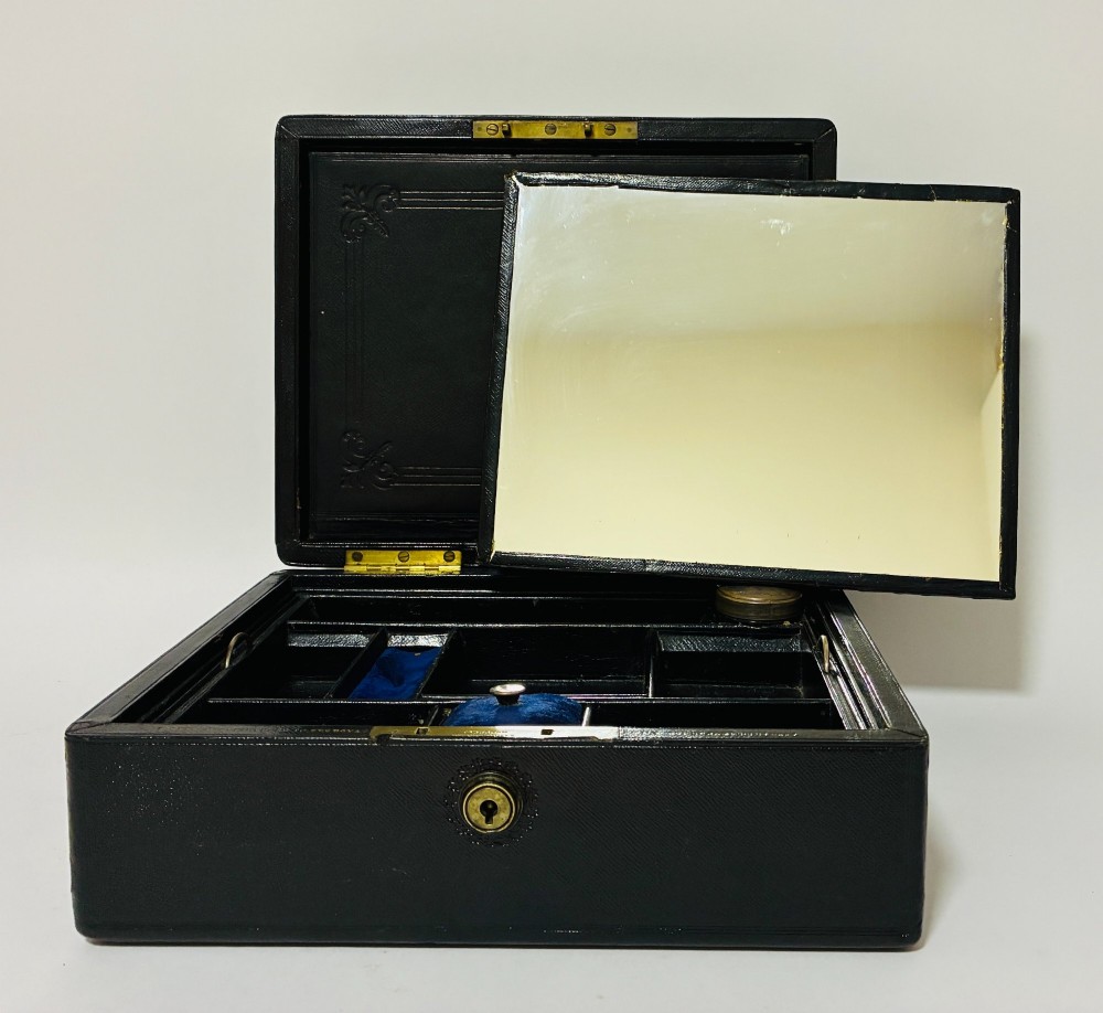 An open Victorian dark brown leather dressing case with a blue velvet-lined lid, brass lock, and compartmentalised interior sitting inside an outer leather travel box. View VII