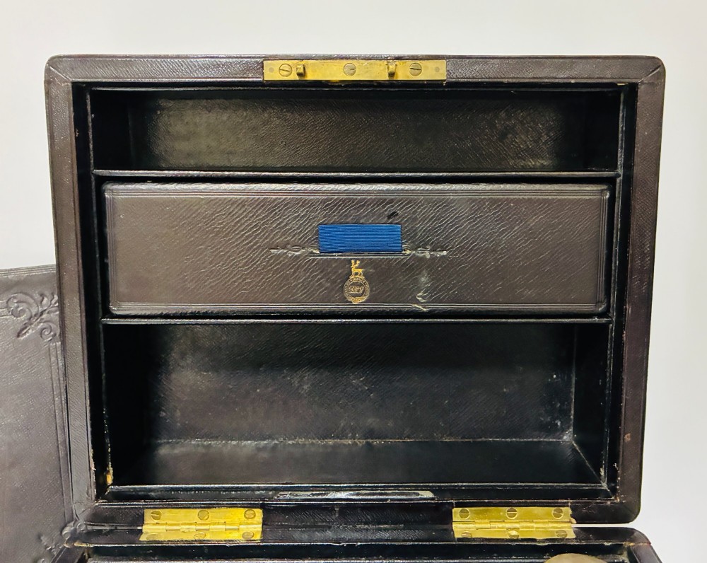 An open Victorian dark brown leather dressing case with a blue velvet-lined lid, brass lock, and compartmentalised interior sitting inside an outer leather travel box. View IX