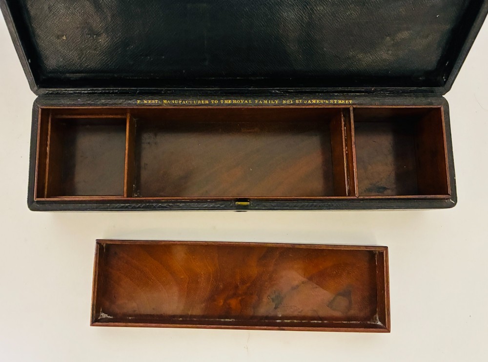 An open Victorian dark brown leather dressing case with a blue velvet-lined lid, brass lock, and compartmentalised interior sitting inside an outer leather travel box. View X