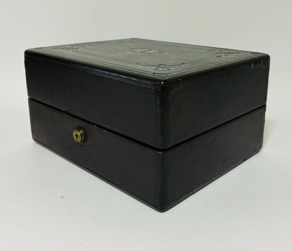 An open Victorian dark brown leather dressing case with a blue velvet-lined lid, brass lock, and compartmentalised interior sitting inside an outer leather travel box. View XI