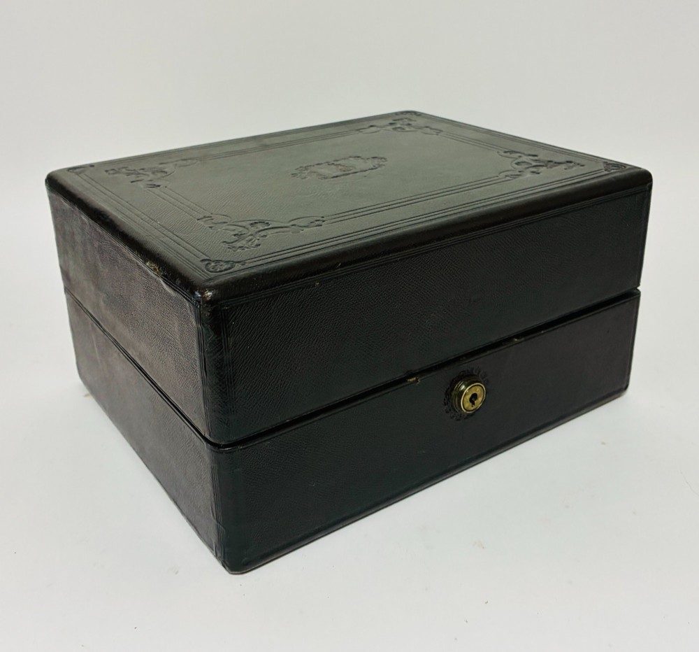 An open Victorian dark brown leather dressing case with a blue velvet-lined lid, brass lock, and compartmentalised interior sitting inside an outer leather travel box. View XII