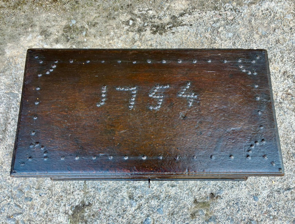An 18th-century dark oak strong box featuring nail-head studs forming the date 1754 on the lid and three keyholes along the front fascia. View II