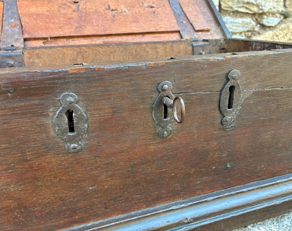 An 18th-century dark oak strong box featuring nail-head studs forming the date 1754 on the lid and three keyholes along the front fascia. View VI