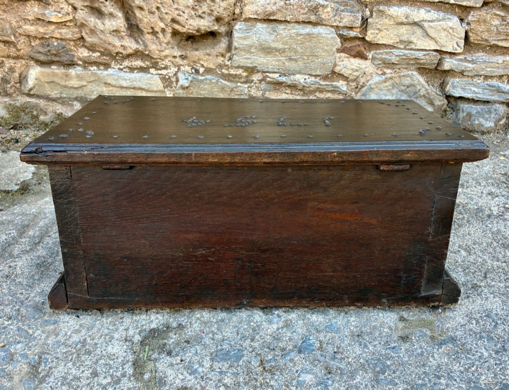 An 18th-century dark oak strong box featuring nail-head studs forming the date 1754 on the lid and three keyholes along the front fascia. View X