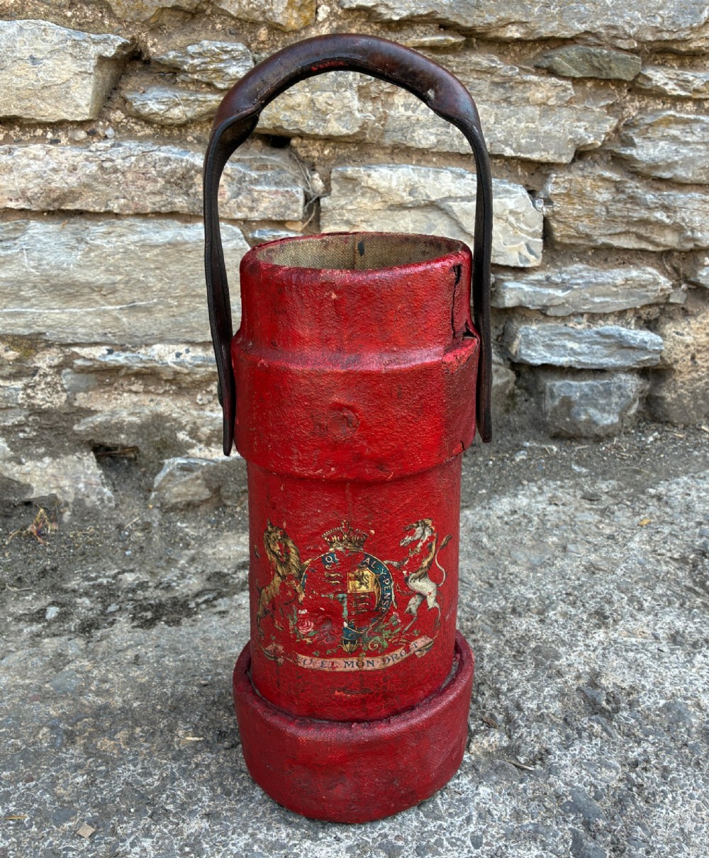 A cylindrical red leather military cordite carrier featuring a hand-painted Royal Coat of Arms and an attached leather handle.