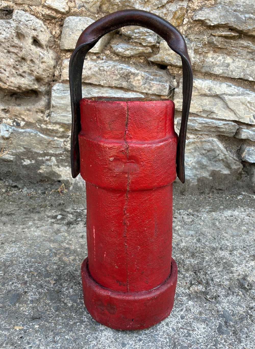 A cylindrical red leather military cordite carrier featuring a hand-painted Royal Coat of Arms and an attached leather handle. View IV