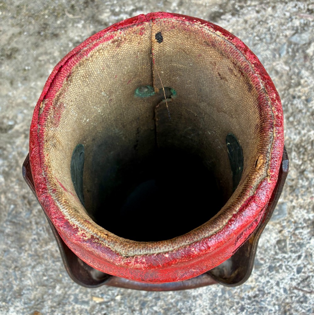 A cylindrical red leather military cordite carrier featuring a hand-painted Royal Coat of Arms and an attached leather handle. View IX