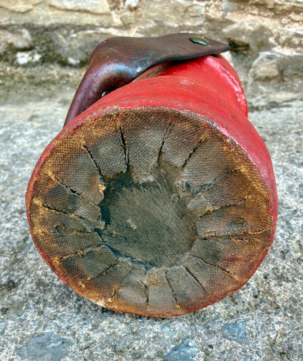 A cylindrical red leather military cordite carrier featuring a hand-painted Royal Coat of Arms and an attached leather handle. View X
