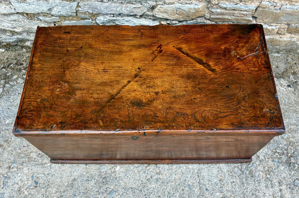 A rectangular antique elm blanket box featuring a hinged lid, visible wood grain, and a central keyhole escutcheon. View II