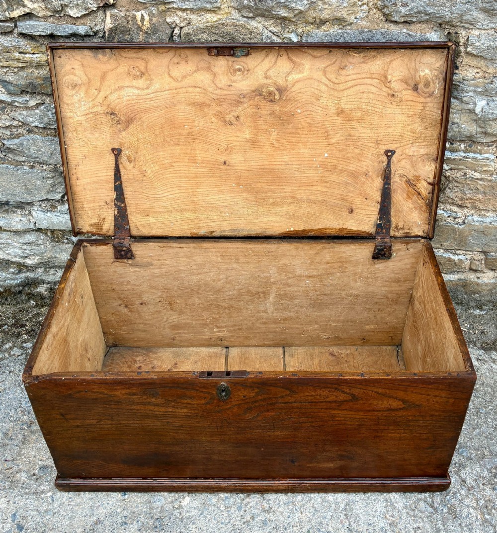 A rectangular antique elm blanket box featuring a hinged lid, visible wood grain, and a central keyhole escutcheon. View III