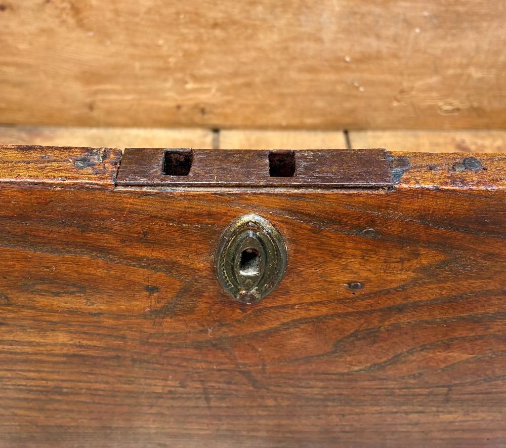 A rectangular antique elm blanket box featuring a hinged lid, visible wood grain, and a central keyhole escutcheon. View VII