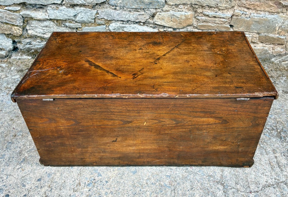 A rectangular antique elm blanket box featuring a hinged lid, visible wood grain, and a central keyhole escutcheon. View XII