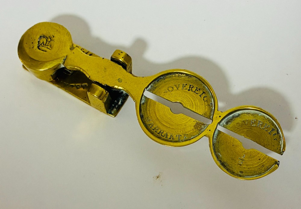 A Victorian brass rocker scale designed for testing gold sovereign coins against a plain white background. View II