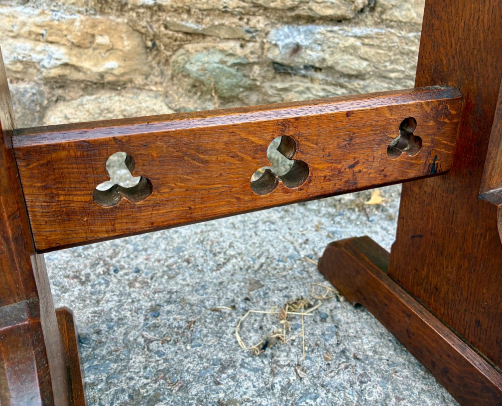 A small antique dark oak church lectern featuring a slanted reading top, trefoil cutouts, and a trestle base. View IX