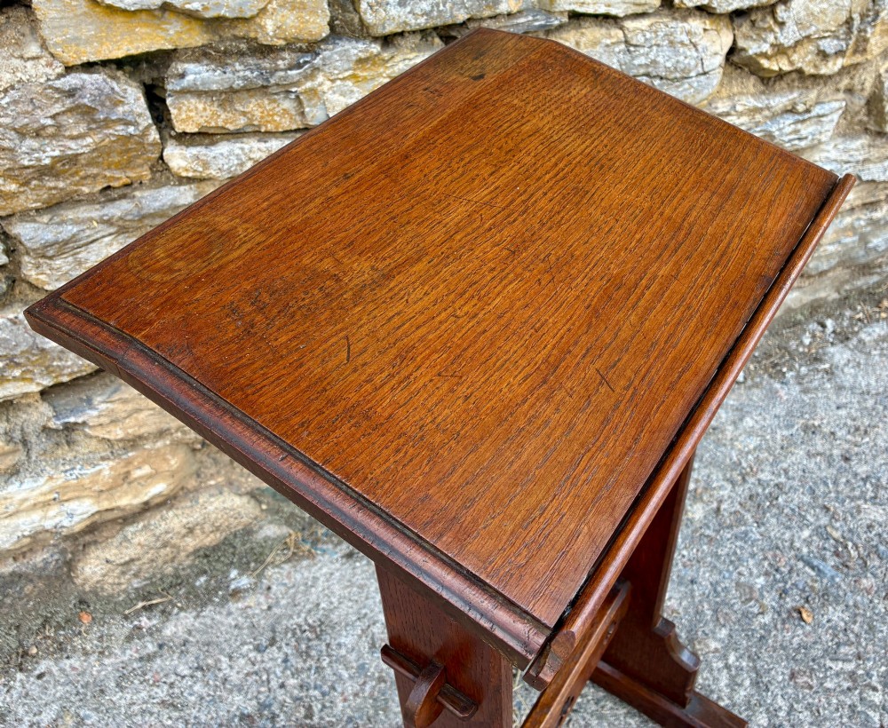 A small antique dark oak church lectern featuring a slanted reading top, trefoil cutouts, and a trestle base. View XI