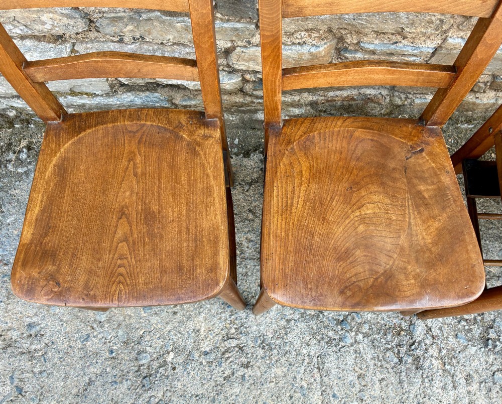 A set of four matching antique wooden chapel chairs with contoured seats and ladder-back rails. View VII