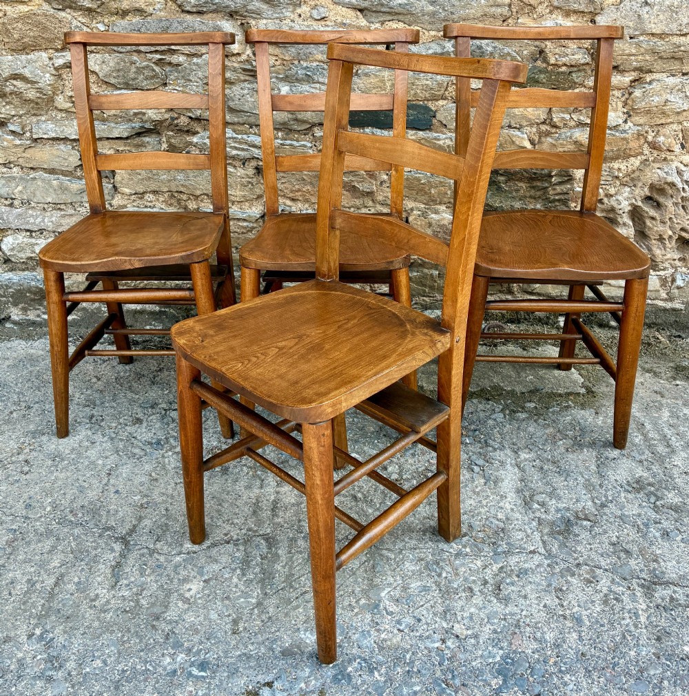 A set of four matching antique wooden chapel chairs with contoured seats and ladder-back rails. View VIII