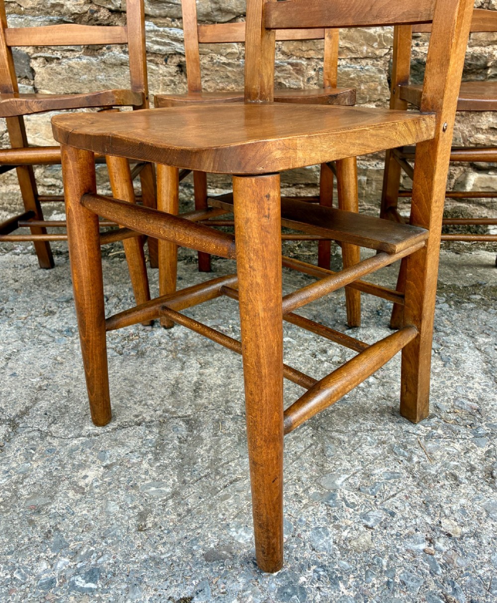 A set of four matching antique wooden chapel chairs with contoured seats and ladder-back rails. View IX