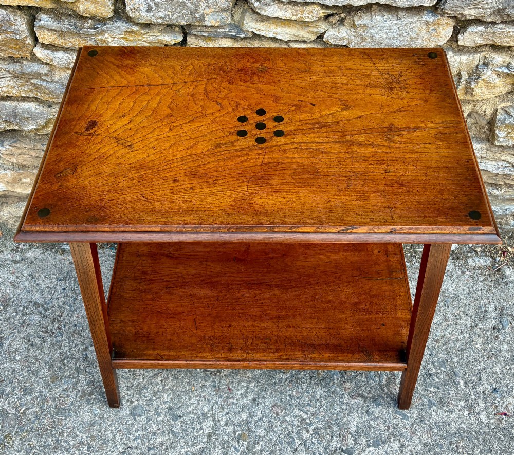 An Arts and Crafts solid oak side table featuring a lower shelf, straight square legs, and dark circular wood inlays arranged in a grid pattern on the top surface. View III