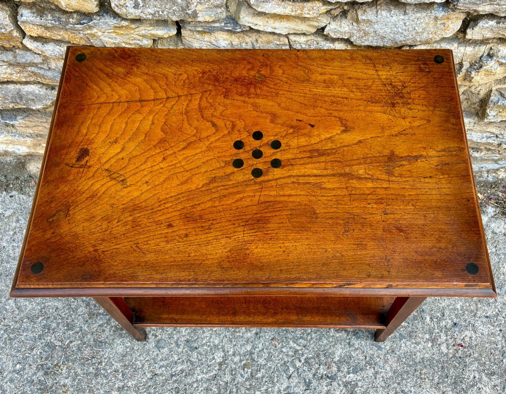 An Arts and Crafts solid oak side table featuring a lower shelf, straight square legs, and dark circular wood inlays arranged in a grid pattern on the top surface. View IV