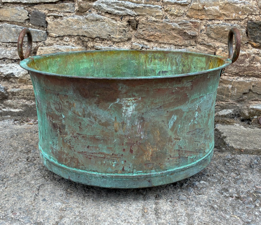 A large circular antique copper wash tub displaying heavy green verdigris oxidisation and two iron side handles. View II