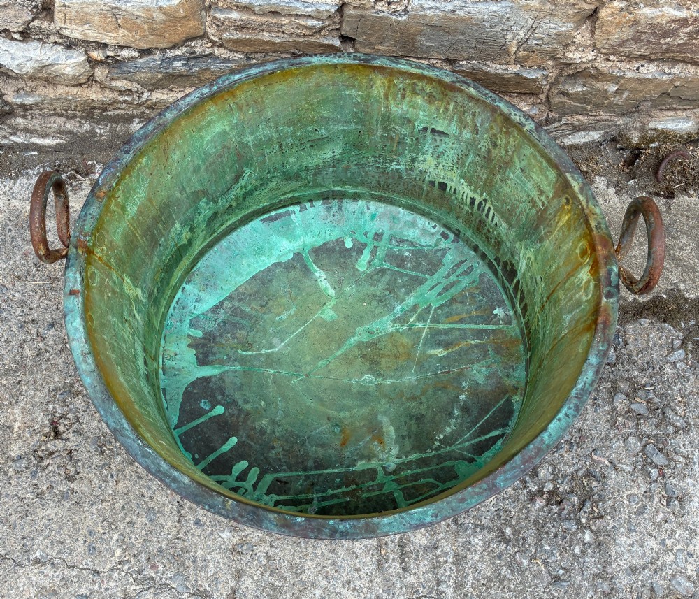 A large circular antique copper wash tub displaying heavy green verdigris oxidisation and two iron side handles. View III