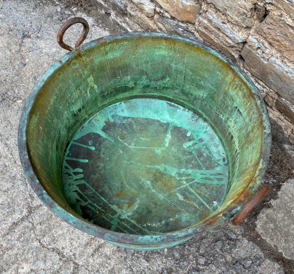A large circular antique copper wash tub displaying heavy green verdigris oxidisation and two iron side handles. View IV