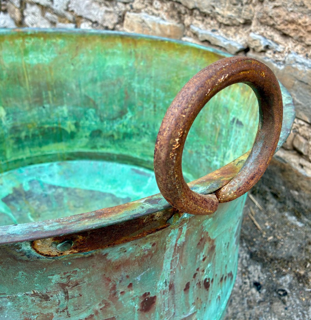 A large circular antique copper wash tub displaying heavy green verdigris oxidisation and two iron side handles. View V