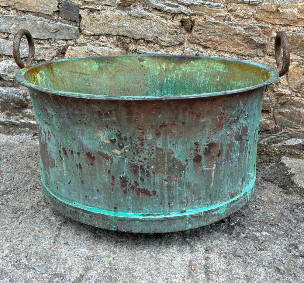 A large circular antique copper wash tub displaying heavy green verdigris oxidisation and two iron side handles. View IX
