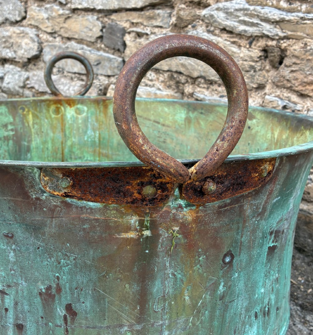 A large circular antique copper wash tub displaying heavy green verdigris oxidisation and two iron side handles. View X