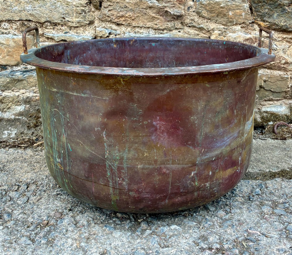 A large, circular antique copper wash tub featuring twin wrought iron carrying handles, a rolled rim, and heavy surface oxidisation with verdigris. View II