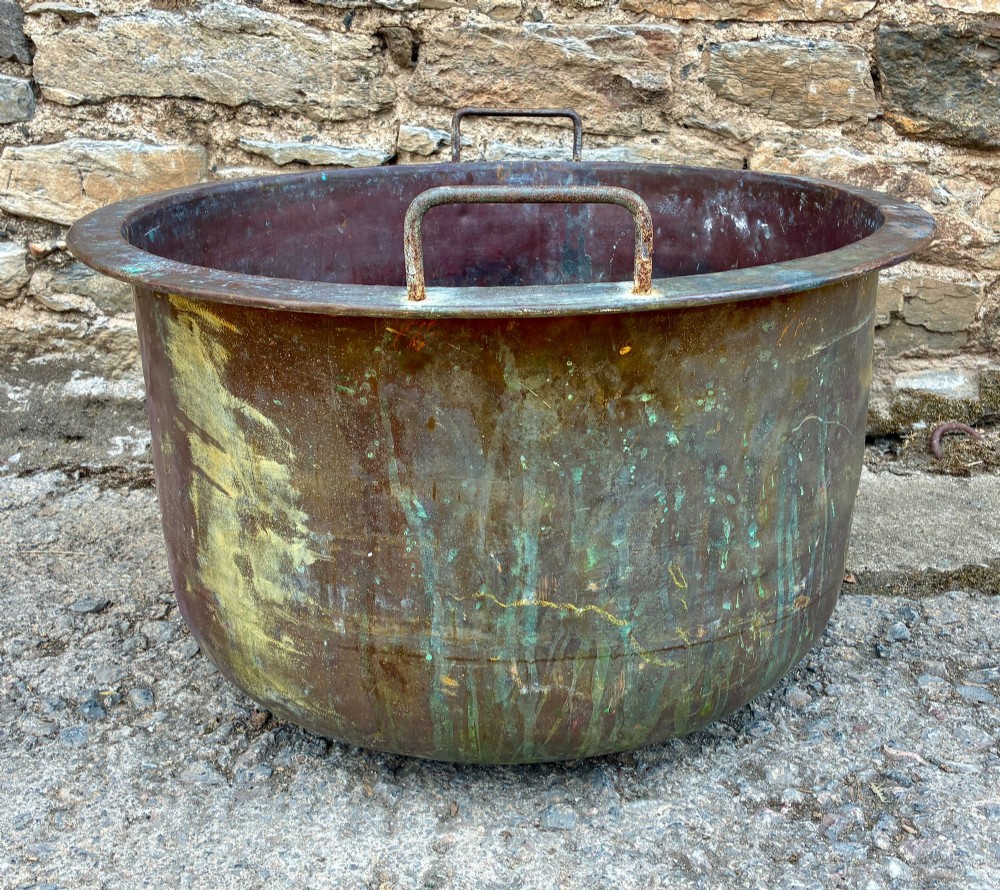 A large, circular antique copper wash tub featuring twin wrought iron carrying handles, a rolled rim, and heavy surface oxidisation with verdigris. View VII
