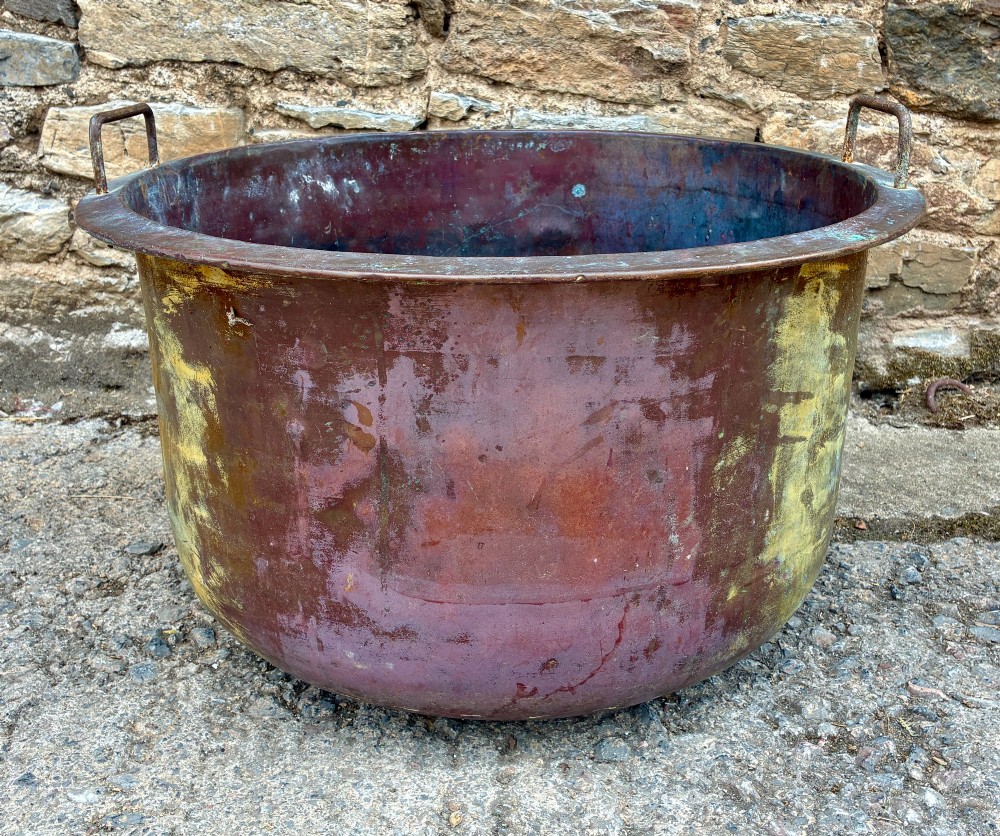A large, circular antique copper wash tub featuring twin wrought iron carrying handles, a rolled rim, and heavy surface oxidisation with verdigris. View VIII