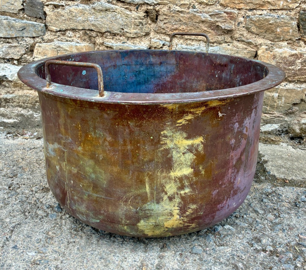 A large, circular antique copper wash tub featuring twin wrought iron carrying handles, a rolled rim, and heavy surface oxidisation with verdigris. View IX