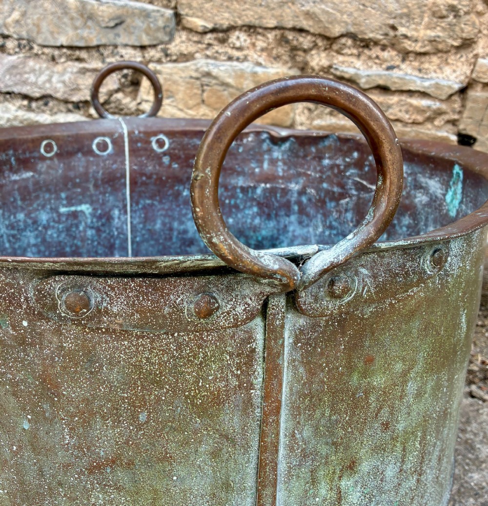 A large cylindrical antique copper wash tub featuring a flared rolled rim, side handles, and a heavily aged green verdigris patina. View V