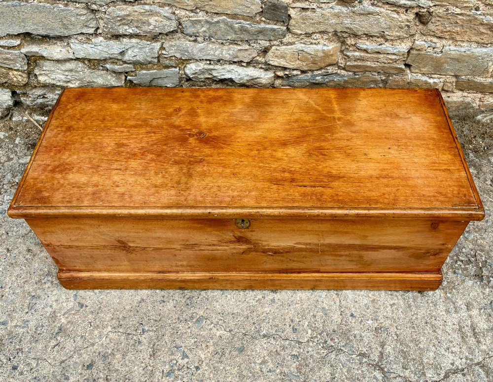 A rectangular pine blanket box featuring a hinged lid, brass keyhole escutcheon, and a low plinth base. View II
