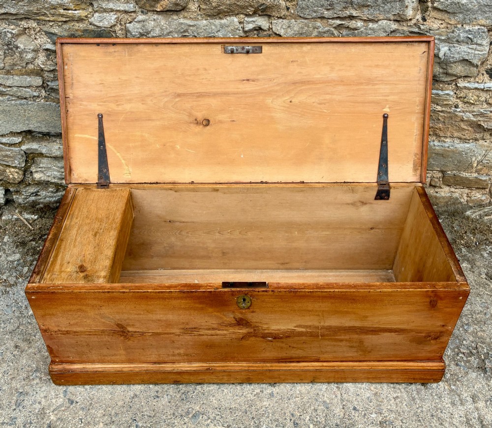 A rectangular pine blanket box featuring a hinged lid, brass keyhole escutcheon, and a low plinth base. View III