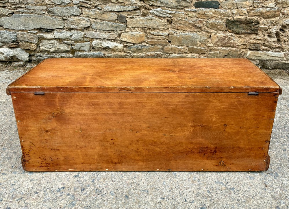 A rectangular pine blanket box featuring a hinged lid, brass keyhole escutcheon, and a low plinth base. View X