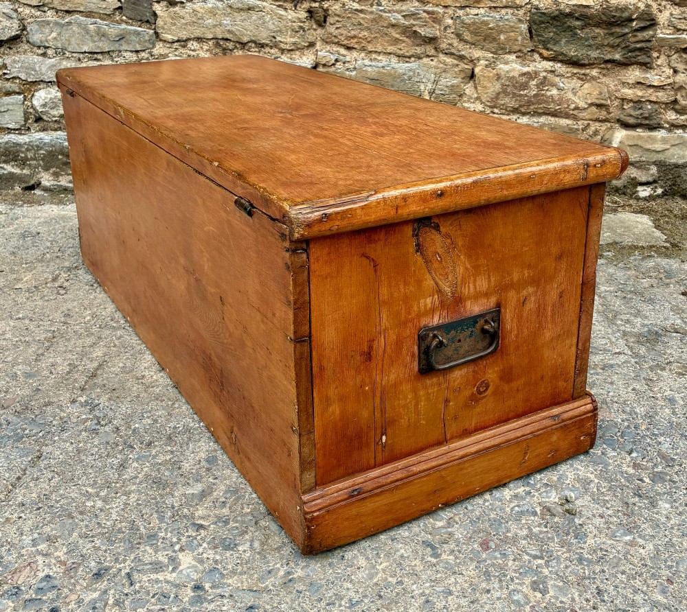 A rectangular pine blanket box featuring a hinged lid, brass keyhole escutcheon, and a low plinth base. View XI