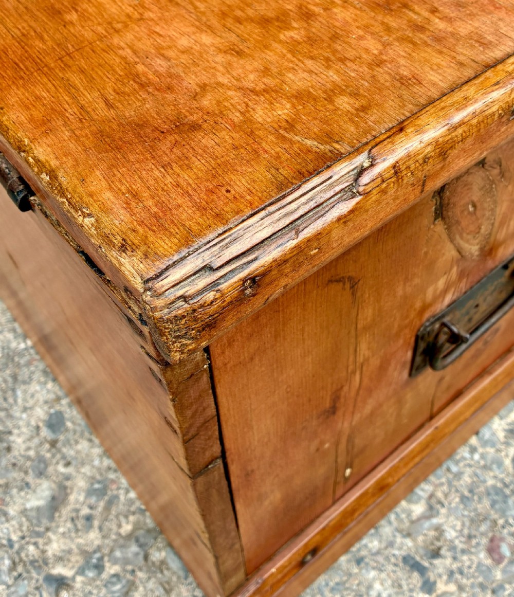 A rectangular pine blanket box featuring a hinged lid, brass keyhole escutcheon, and a low plinth base. View XII