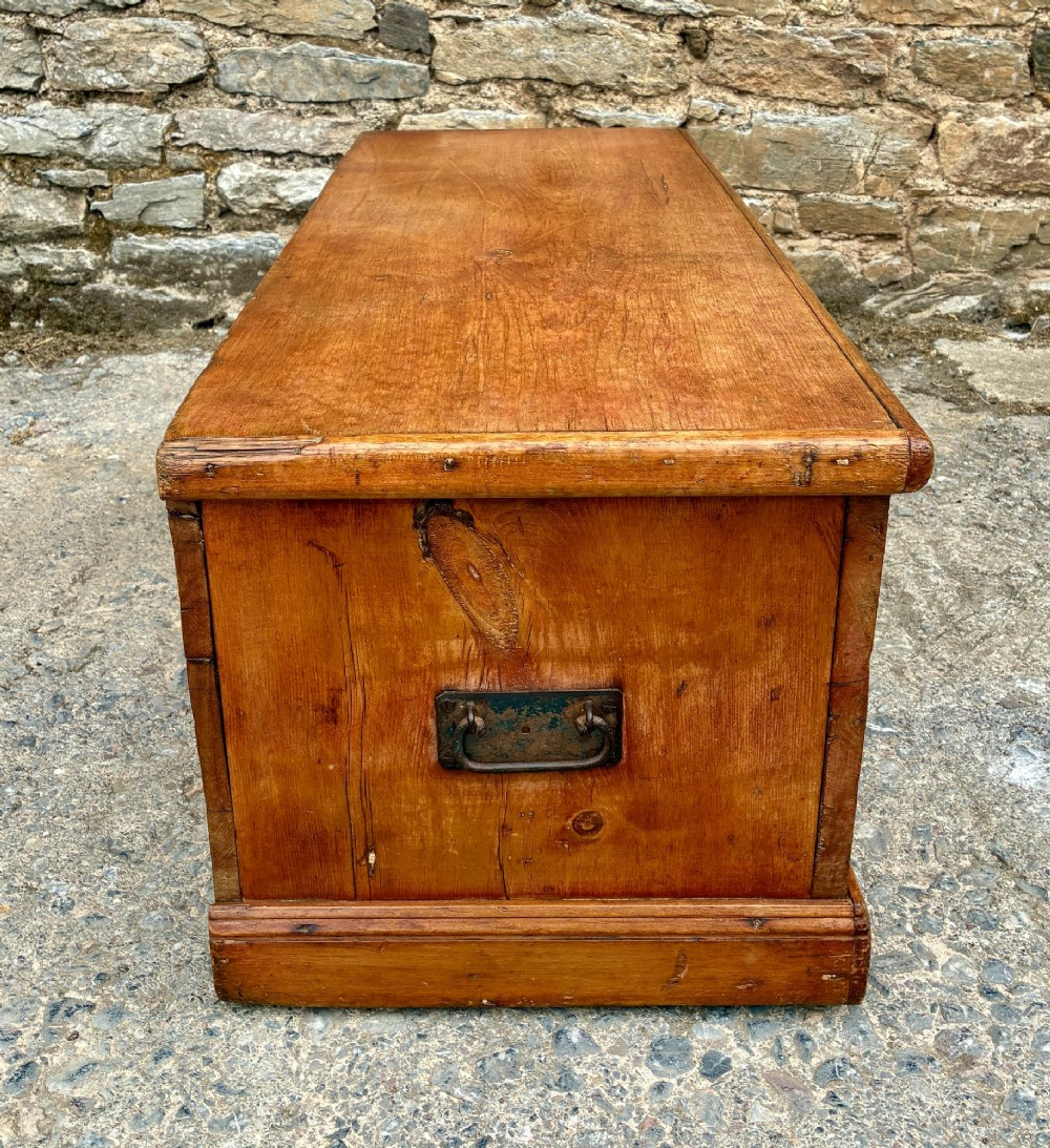 A rectangular pine blanket box featuring a hinged lid, brass keyhole escutcheon, and a low plinth base. View XIII