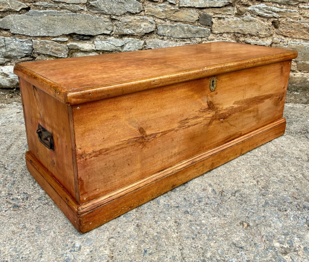 A rectangular pine blanket box featuring a hinged lid, brass keyhole escutcheon, and a low plinth base. View XIV