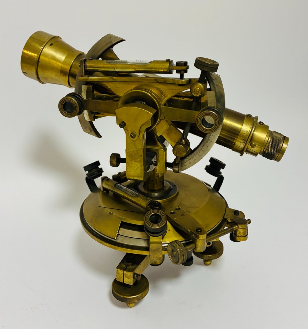 An antique brass surveyors theodolite featuring a central sighting telescope, spirit levels, and knurled adjustment screws on a circular base. View VIII