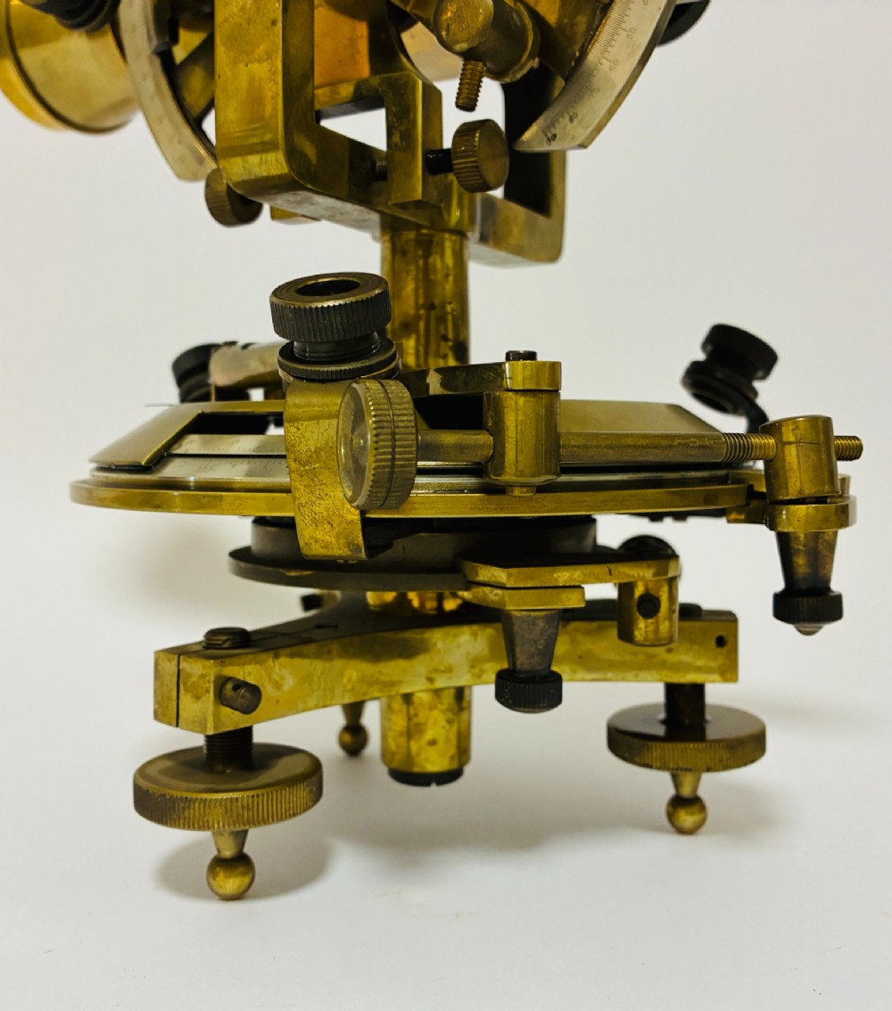 An antique brass surveyors theodolite featuring a central sighting telescope, spirit levels, and knurled adjustment screws on a circular base. View XIV