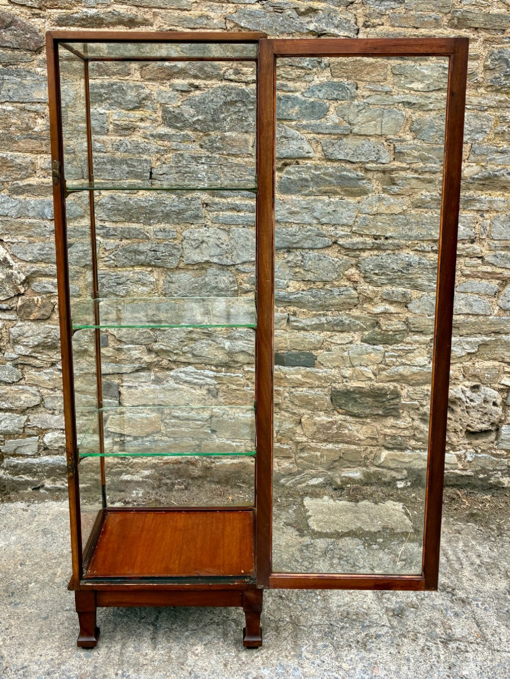 A tall, slim mahogany shop display cabinet featuring glass side panels, a single glazed door, three interior glass shelves, and brass catches. View X