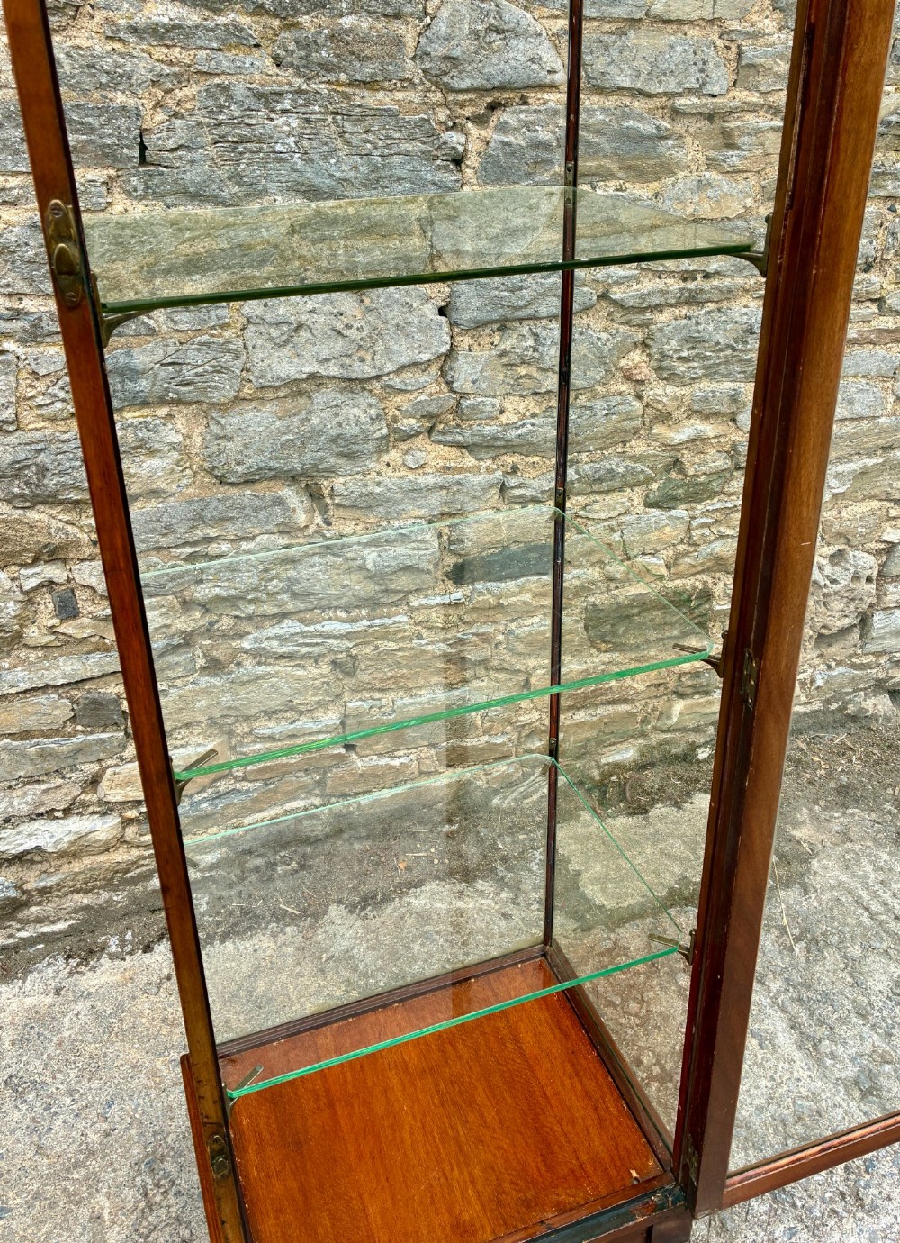 A tall, slim mahogany shop display cabinet featuring glass side panels, a single glazed door, three interior glass shelves, and brass catches. View XI