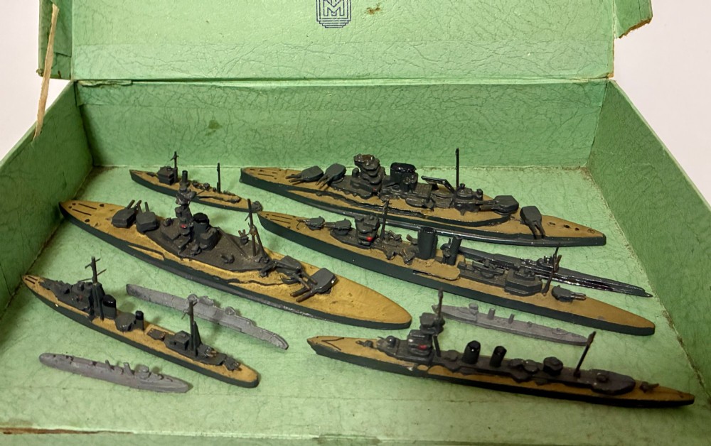 A vintage green cardboard box containing a set of miniature diecast metal model warships of the British Navy. View II